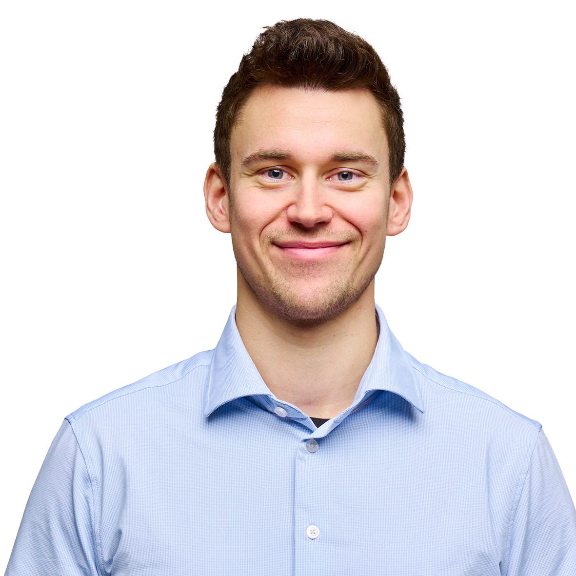 Portræt af en ung mand med kort brunt hår og et venligt smil. Han er iført en lyseblå skjorte og kigger direkte mod kameraet på en hvid baggrund.