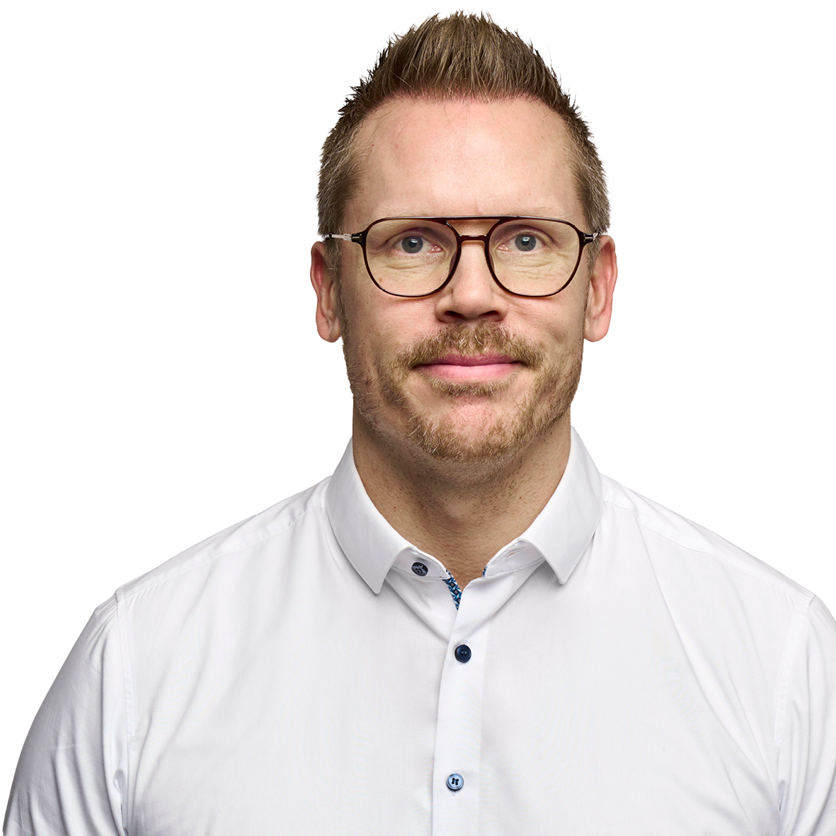 Portrætbillede af en mand med kort, opadstående brunt hår, briller med mørkt stel og skægstubbe. Han er iført en hvid skjorte og kigger direkte ind i kameraet mod en hvid baggrund.